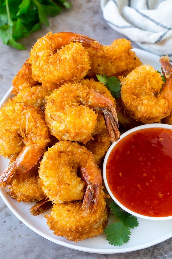 Coconut Shrimp Recipe | Fried Shrimp | Shrimp Appetizer #shrimp #coconut #appetizer #seafood #dinner #uzhal A plate of coconut shrimp with a bowl of sweet chili sauce.