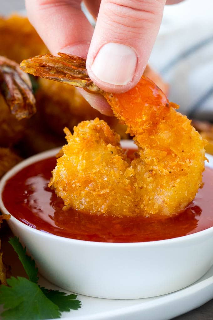 Coconut Shrimp Recipe | Fried Shrimp | Shrimp Appetizer #shrimp #coconut #appetizer #seafood #dinner #uzhal A hand dipping a crispy prawn into a bowl of sweet chili sauce.