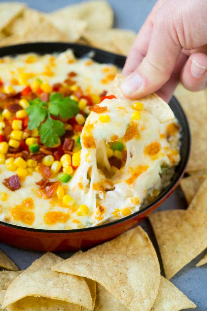 Corn Dip Recipe | Hot Cheese Dip | Bacon Dip #corn #dip #bacon #cheese #appetizer #snack #uzhal A chip scooping up a serving of corn dip.
