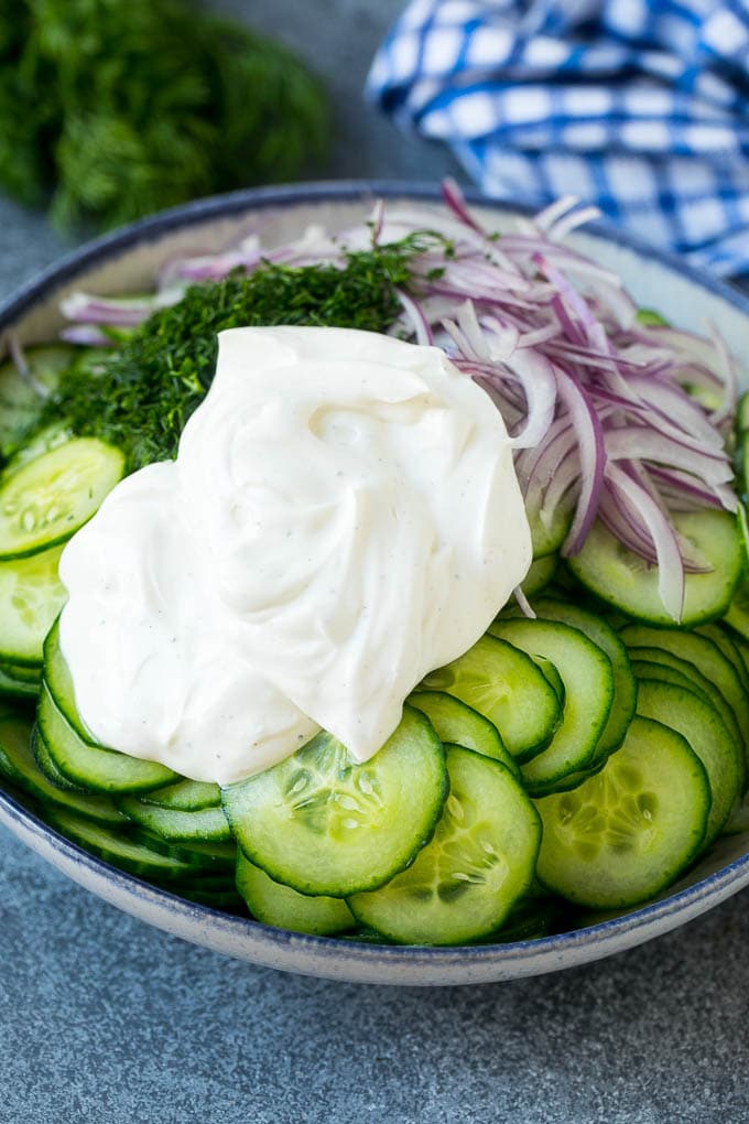 Creamy Cucumber Salad Recipe | German Cucumber Salad | Cucumber Salad #cucumber #salad #dinner #lunch #uzhal #cucumbersalad Cucumbers, red onion and dill in a bowl topped with creamy dressing.