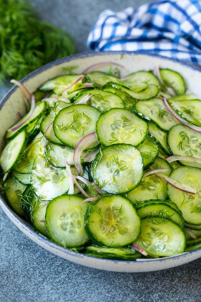 A bowl of cucumber salad with red onion, thinly sliced cucumbers and chopped dill.