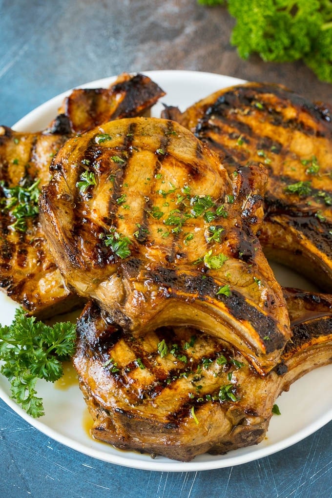 Pork Chop Marinade Recipe | Marinated Pork Chops | Grilled Pork Chops #pork #porkchops #grilling #dinner #uzhal Pork chop marinade on grilled pork chops. The pork chops are on a serving plate garnished with parsley.