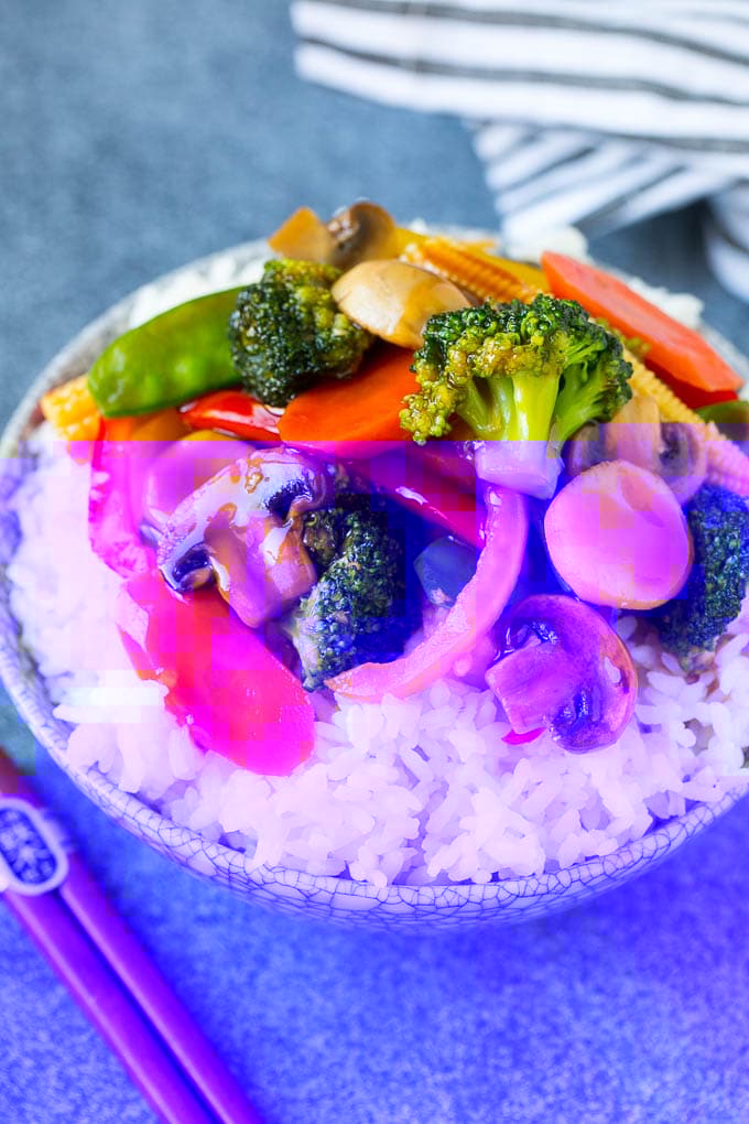 Vegetable stir fry served over rice in a bowl.