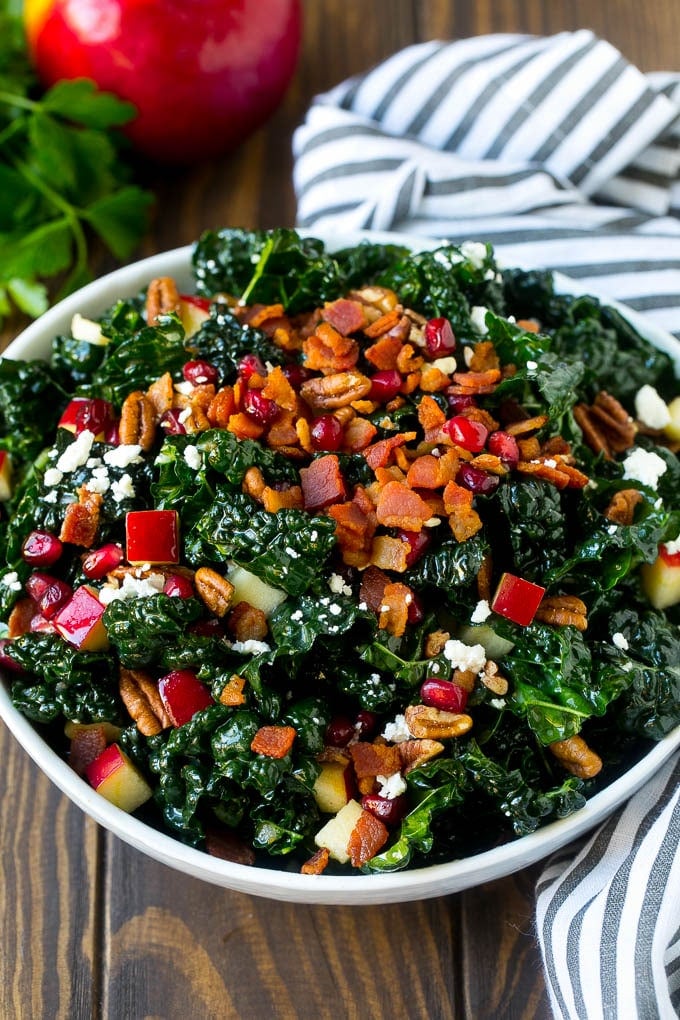 Apple Kale Salad Recipe | Kale Recipe | Fall Salad #kale #apples #bacon #salad #feta #dinner #lunch #uzhal A bowl of tuscan kale salad garnished with cooked bacon.