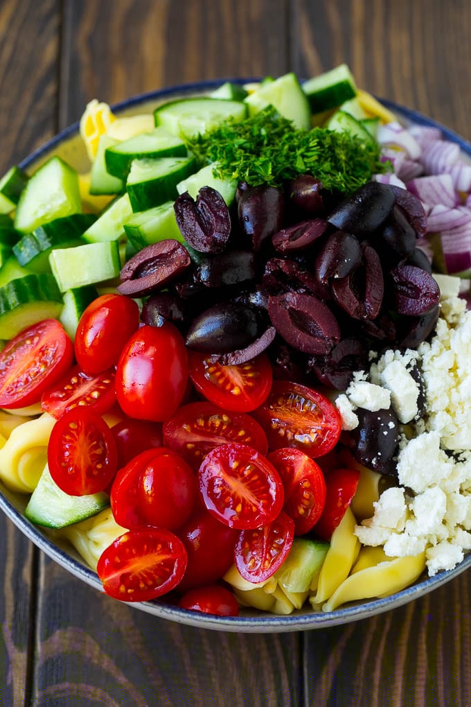 Greek Tortellini Salad Recipe | Pasta Salad | Tortellini Salad | Greek Salad #greek #tortellini #pasta #salad #cucumbers #olives #dinner #uzhal Tortellini in a bowl topped with olives, tomatoes, cucumber and feta cheese.