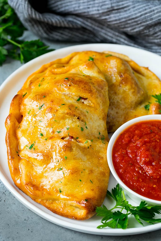 Calzone Recipe | Pizza Pockets #pizza #calzone #pepperoni #sausage #peppers #dinner #uzhal #cheese A homemade calzone served with pizza sauce.