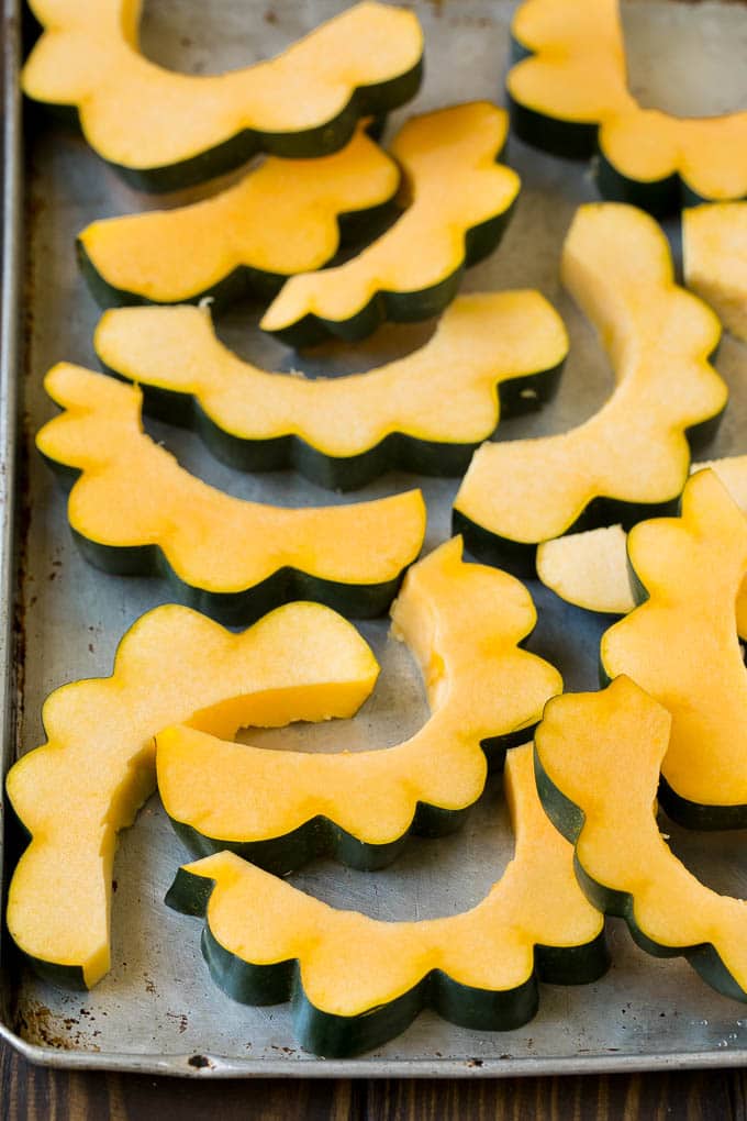 Sliced acorn squash on a sheet pan.