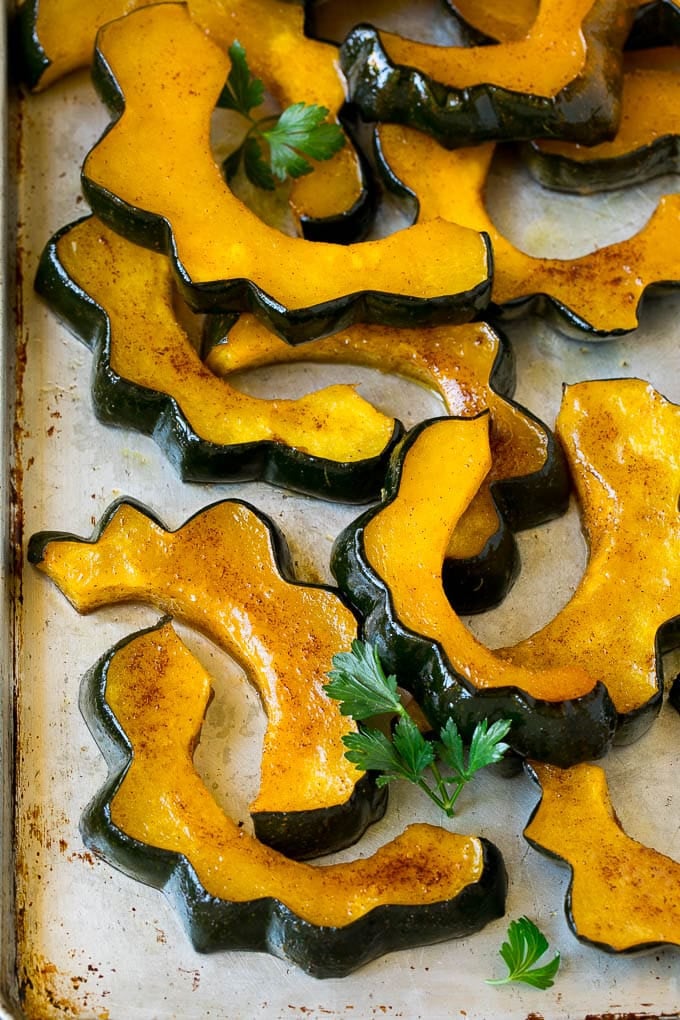 Sliced of cinnamon roasted acorn squash on a sheet pan.