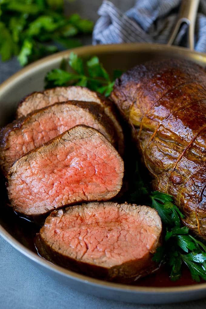 Beef Tenderloin with Garlic Butter #beef #steak #dinner #uzhal A sliced beef tenderloin recipe in a pan, garnished with fresh parsley.