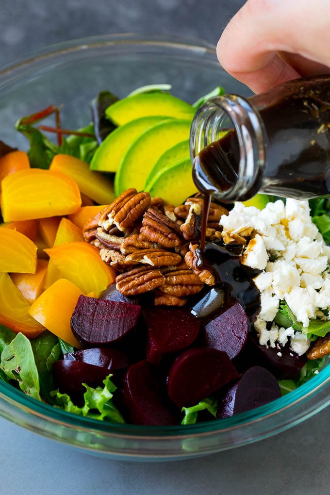 Beet Salad Recipe #beets #avocado #feta #salad #dinner #uzhal Balsamic dressing being poured over beets, sliced avocado and feta cheese.