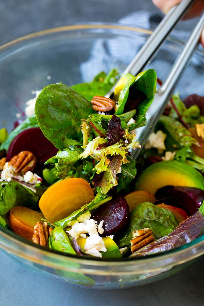 Beet Salad Recipe #beets #avocado #feta #salad #dinner #uzhal Tongs serving a portion of beet salad tossed in balsamic dressing.