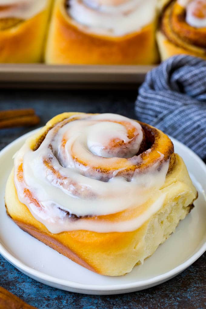 Cinnamon Rolls Recipe | Cinnamon Buns #cinnamon #rolls #pastry #breakfast #brunch #sweets #uzhal #baking #bread A frosted cinnamon bun on a serving plate.