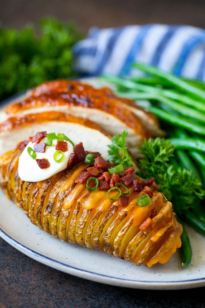 Hasselback Potatoes Recipe #potatoes #bacon #sidedish #cheese #dinner #uzhal Hasselback potatoes on a plate, served with turkey and green beans.