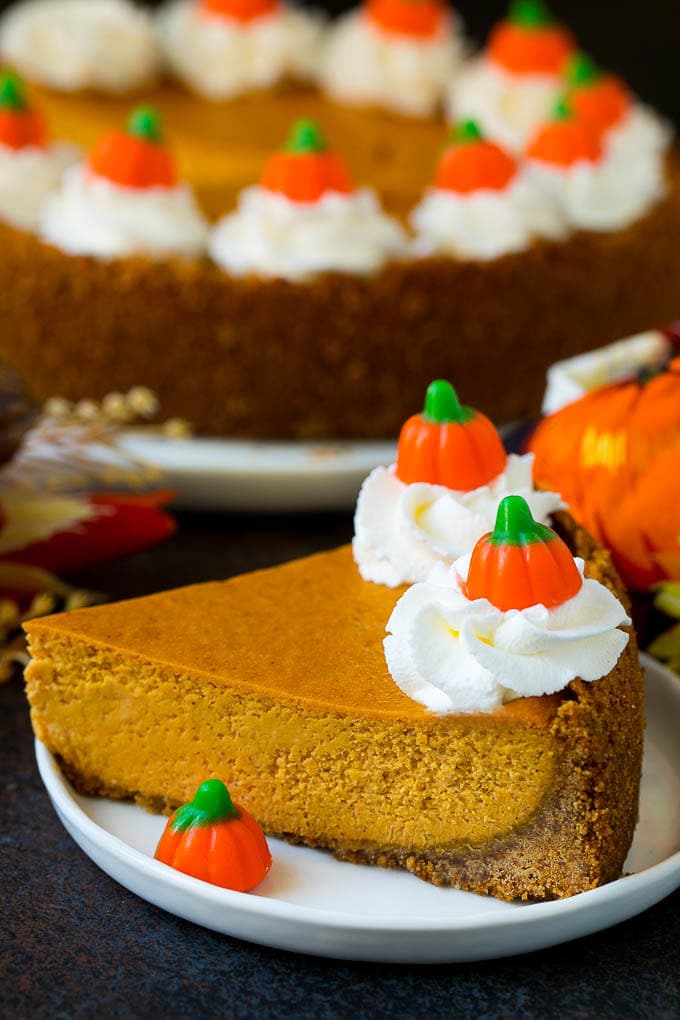 Pumpkin Pie Cheesecake Recipe | Pumpkin Cheesecake #cake #cheesecake #pumpkin #fall #thanksgiving #dessert #uzhal A slice of pumpkin pie cheesecake garnished with whipped cream.