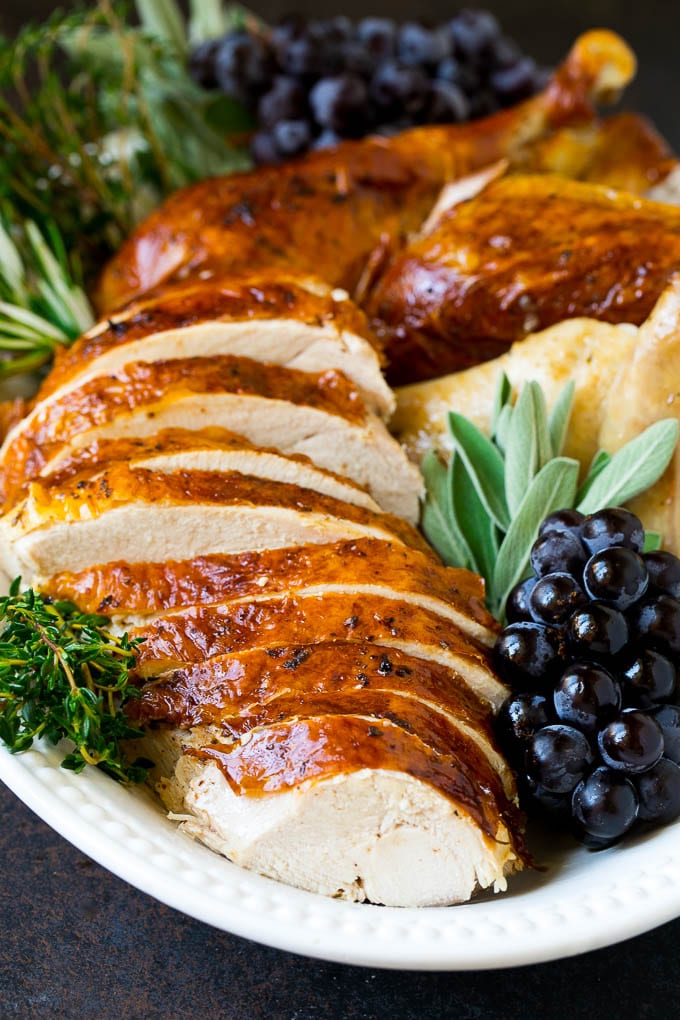 Sliced Thanksgiving turkey on a serving platter with fresh herbs.