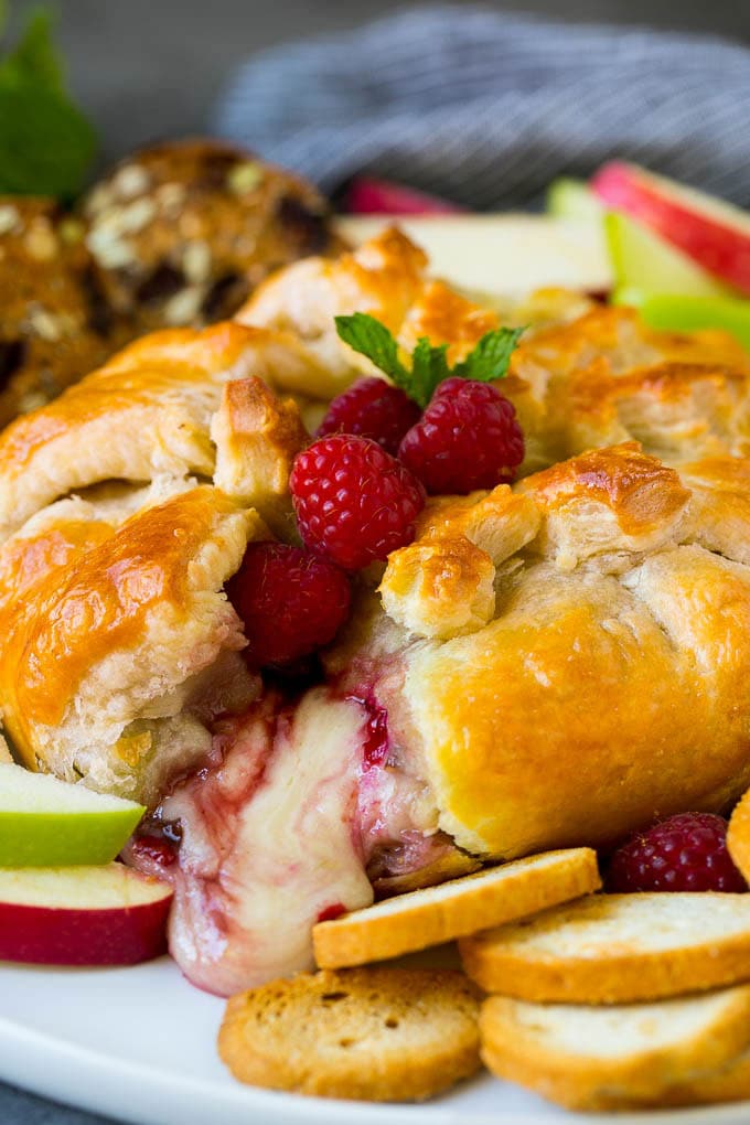 Baked Brie Recipe | Pastry Wrapped Brie #brie #cheese #appetizer #pecans #raspberries #uzhal Baked brie cut open with cheese spilling out.
