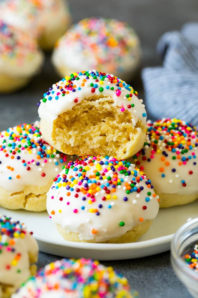 Italian Cookies Recipe | Almond Cookies #cookies #italianfood #frosting #sprinkles #baking #christmas #uzhal A plate of Italian cookies with a bite taken out of one.
