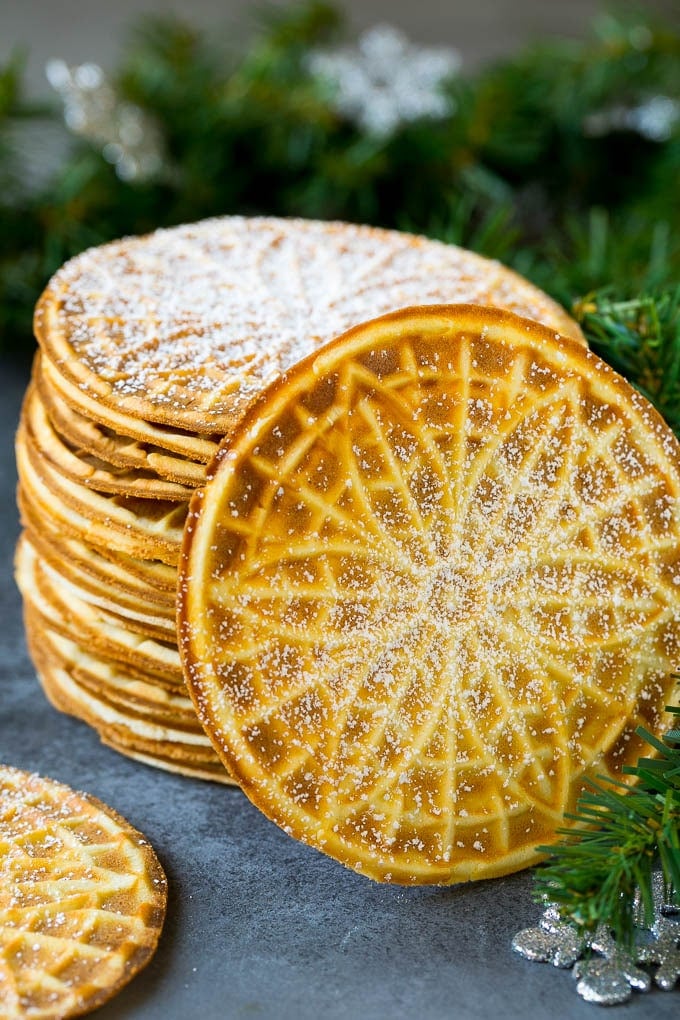 Pizzelle Cookies Recipe #cookies #baking #dessert #christmas #uzhal A stack of pizzelle cookies dusted with powdered sugar.