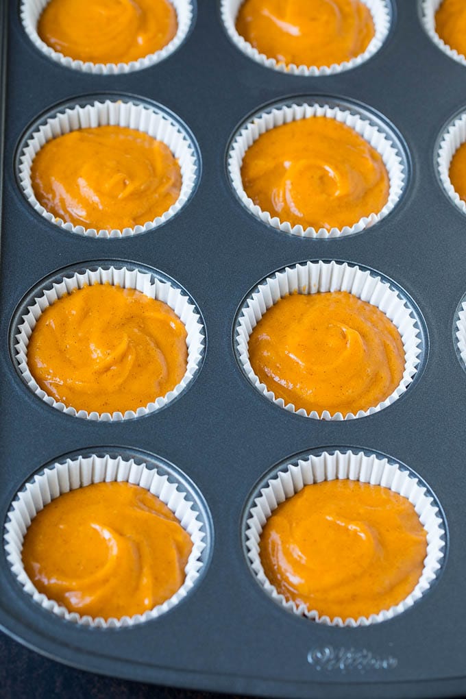 Pumpkin Cupcakes Recipe | Pumpkin Cake #cake #cupcakes #pumpkin #frosting #baking #fall #thanksgiving #uzhal Batter inside paper cups in a muffin tin.
