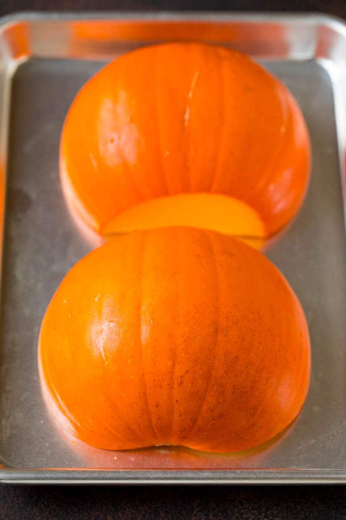 Pumpkin Puree Recipe #pumpkin #baking #fall #thanksgiving #uzhal A pumpkin cut in half on a sheet pan.