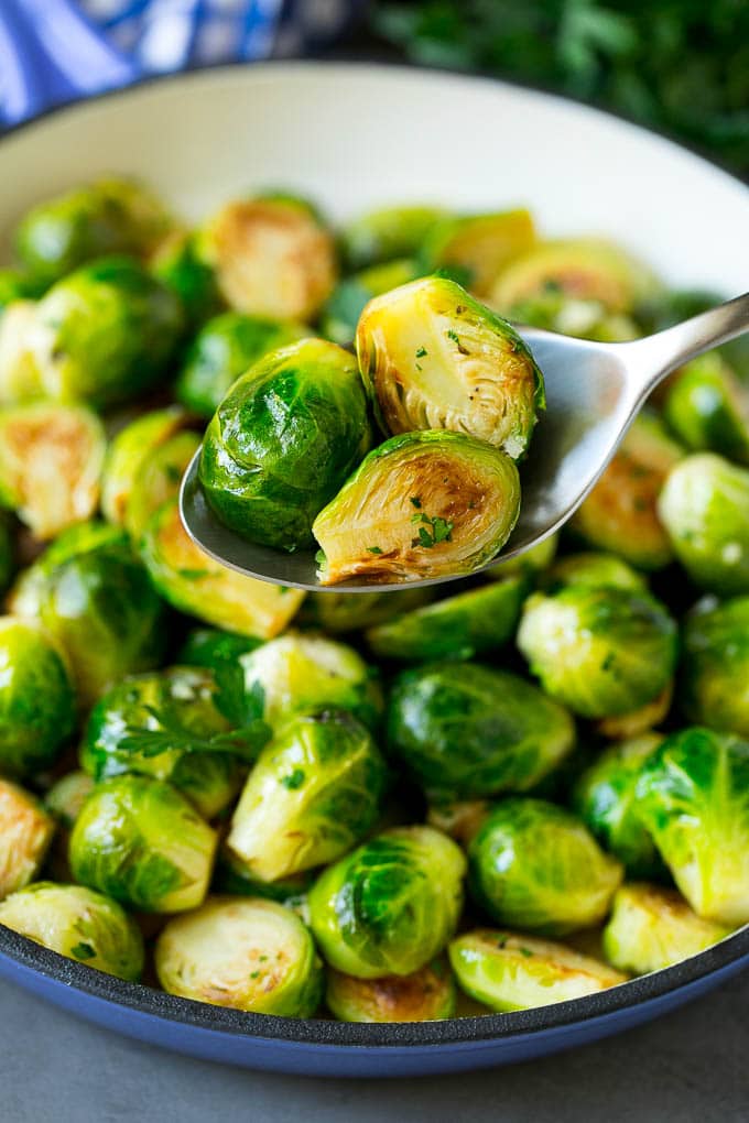 Sauteed Brussels Sprouts Recipe | Brussels Sprouts Side Dish #brusselssprouts #sprouts #veggies #sidedish #garlic #vegetarian #dinner #uzhal A spoon holding up a serving of cooked brussels sprouts.