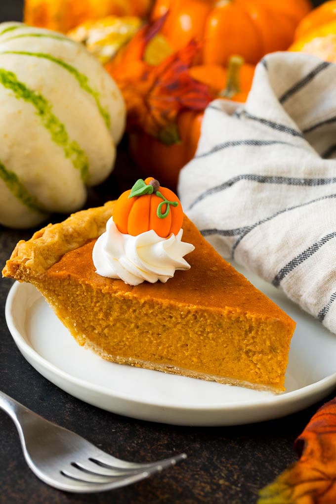 Homemade Pumpkin Pie Recipe | Pumpkin Pie #pie #pumpkin #baking #thanksgiving #fall #dessert #uzhal A slice of homemade pumpkin pie topped with whipped cream and a candy pumpkin.