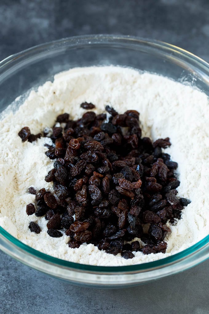 Irish Soda Bread Recipe #bread #baking #stpatricksday #sidedish #uzhal Flour, sugar, butter, baking powder and raisins in a mixing bowl.