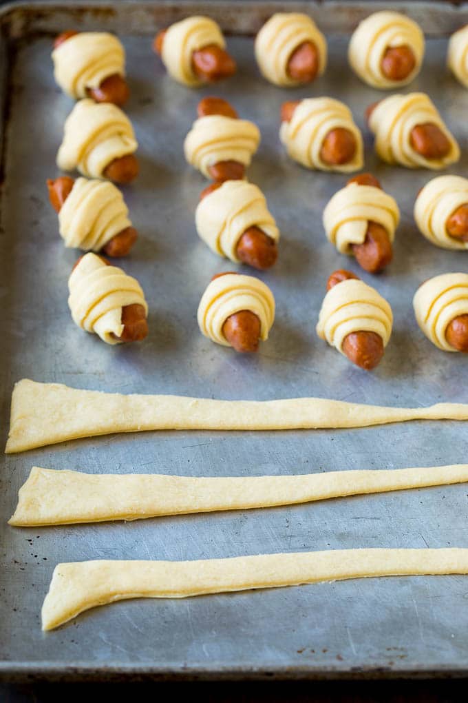 Pigs in a Blanket Recipe #hotdogs #appetizer #snack #comfortfood #uzhal Strips of crescent dough on a sheet pan.