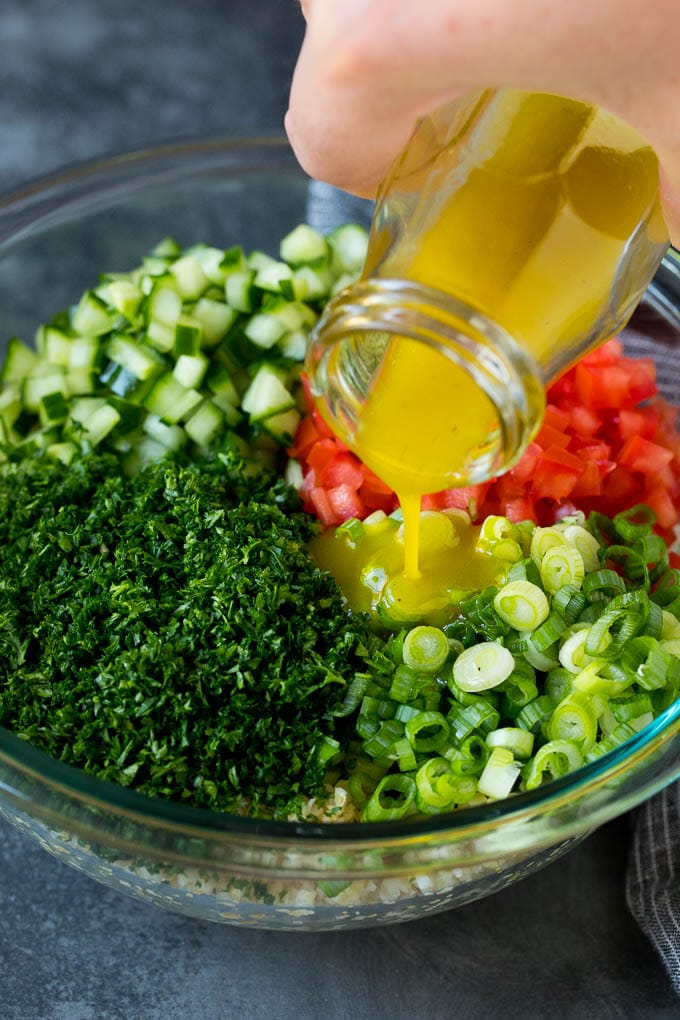 Tabbouleh Salad | Tabouli #salad #wheat #tomatoes #cucumber #healthy #sidedish #dinner #uzhal Dressing being poured into a bowl of bulgur wheat salad.
