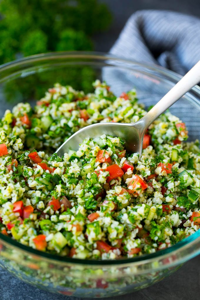 Tabbouleh Salad | Tabouli #salad #wheat #tomatoes #cucumber #healthy #sidedish #dinner #uzhal A bowl of tabbouleh with a serving spoon in it.
