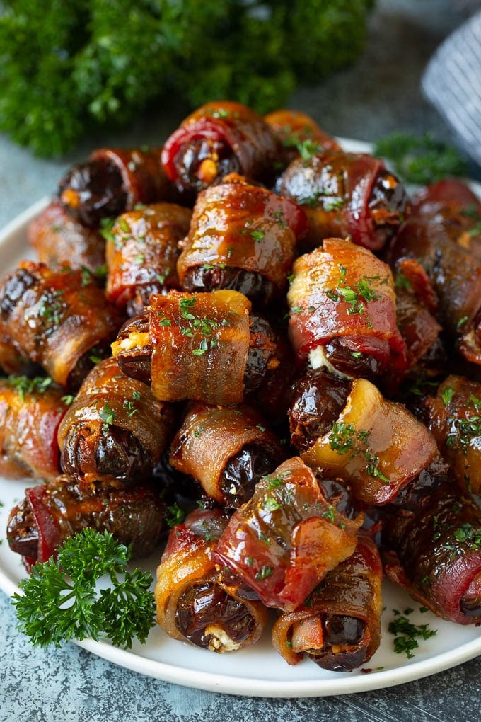 Bacon Wrapped Dates #appetizer #bacon #dates #cheese #uzhal A plate of bacon wrapped dates stuffed with goat cheese.