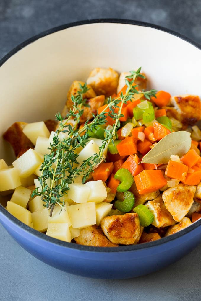 Chicken Pot Pie Soup Recipe | Chicken Soup #soup #chicken #dinner #comfortfood #uzhal Ingredients such as vegetables, potatoes and herbs in a pot.