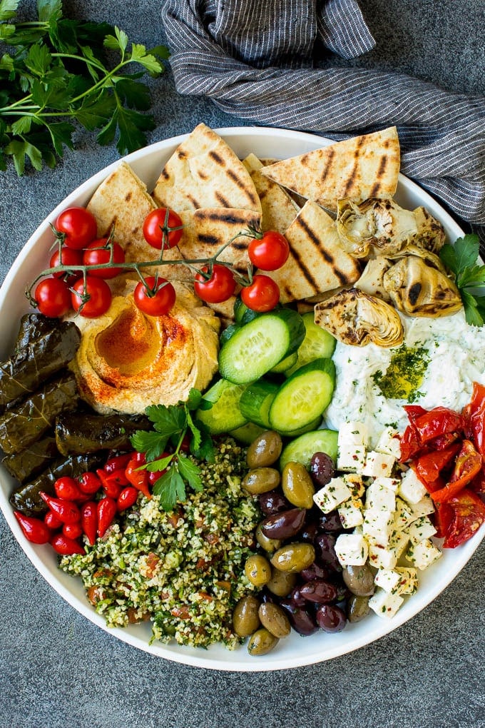 This mezze platter is filled with Mediterranean delicacies including dolmas, hummus, vegetables, pita bread and salads. #appetizer #uzhal A mezze platter filled with dips, pita bread, vegetables, olives and cheese.