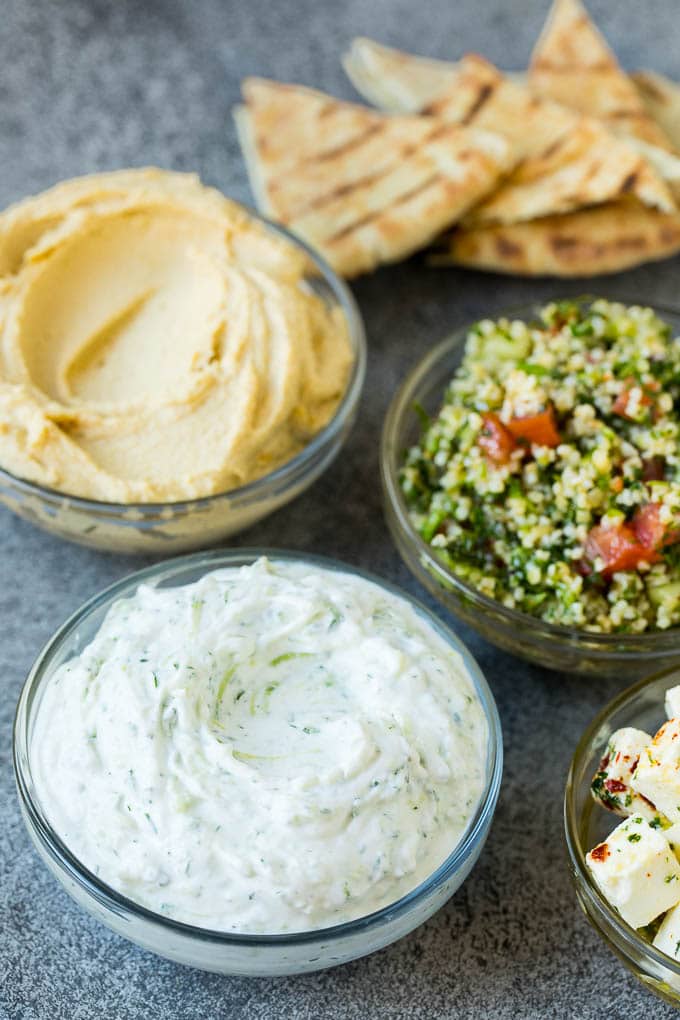 This mezze platter is filled with Mediterranean delicacies including dolmas, hummus, vegetables, pita bread and salads. #appetizer #uzhal Bowls of hummus, tzatziki and tabbouleh.
