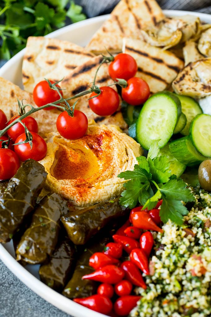This mezze platter is filled with Mediterranean delicacies including dolmas, hummus, vegetables, pita bread and salads. #appetizer #uzhal A Mediterranean mezze platter with hummus, dolmas and vegetables.