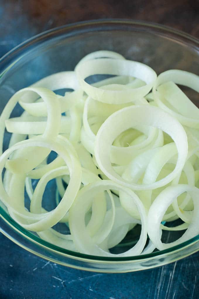 Crispy homemade onion rings that are fried in a flavorful beer batter. #onions #uzhal #appetizer Raw onion slices in a bowl.