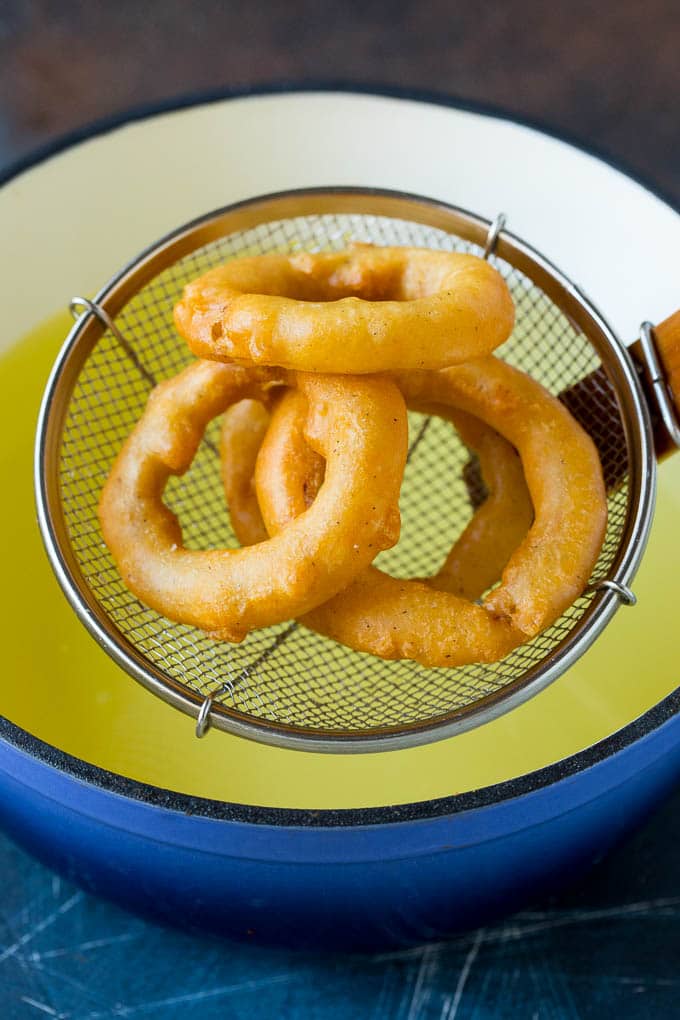 Crispy homemade onion rings that are fried in a flavorful beer batter. #onions #uzhal #appetizer Fried onions coming out of a pot of oil.