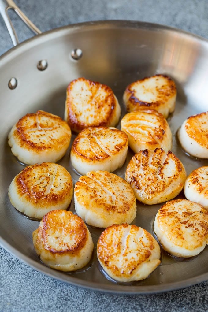 Seared scallops with a garlic and herb butter sauce. An easy and elegant dinner! #seafood #dinner #uzhal Scallops cooked to golden brown in a pan.