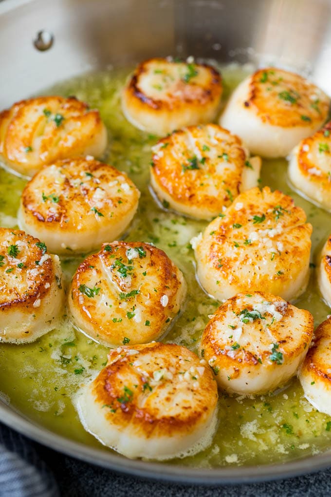 Seared scallops with a garlic and herb butter sauce. An easy and elegant dinner! #seafood #dinner #uzhal A pan of scallops in garlic butter.