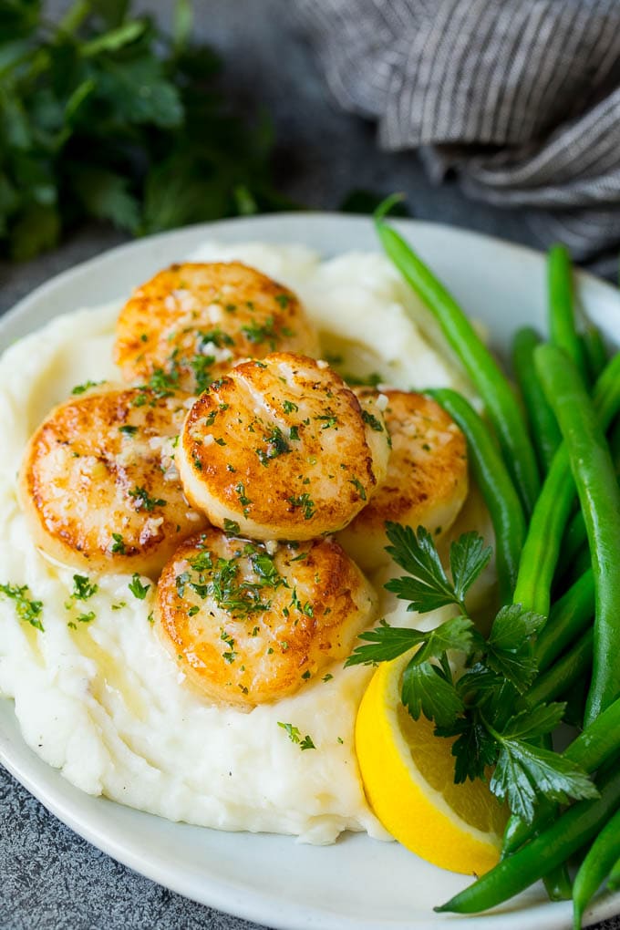 Seared scallops with a garlic and herb butter sauce. An easy and elegant dinner! #seafood #dinner #uzhal Seared scallops served with mashed potatoes and green beans.