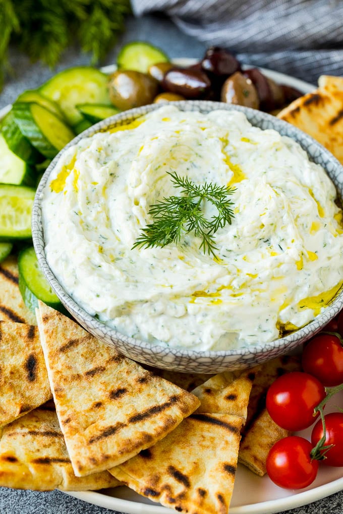 The best homemade tzatziki sauce with cucumber and herbs mixed into Greek yogurt. #appetizer #uzhal A bowl of tzatziki served with pita bread and vegetables.