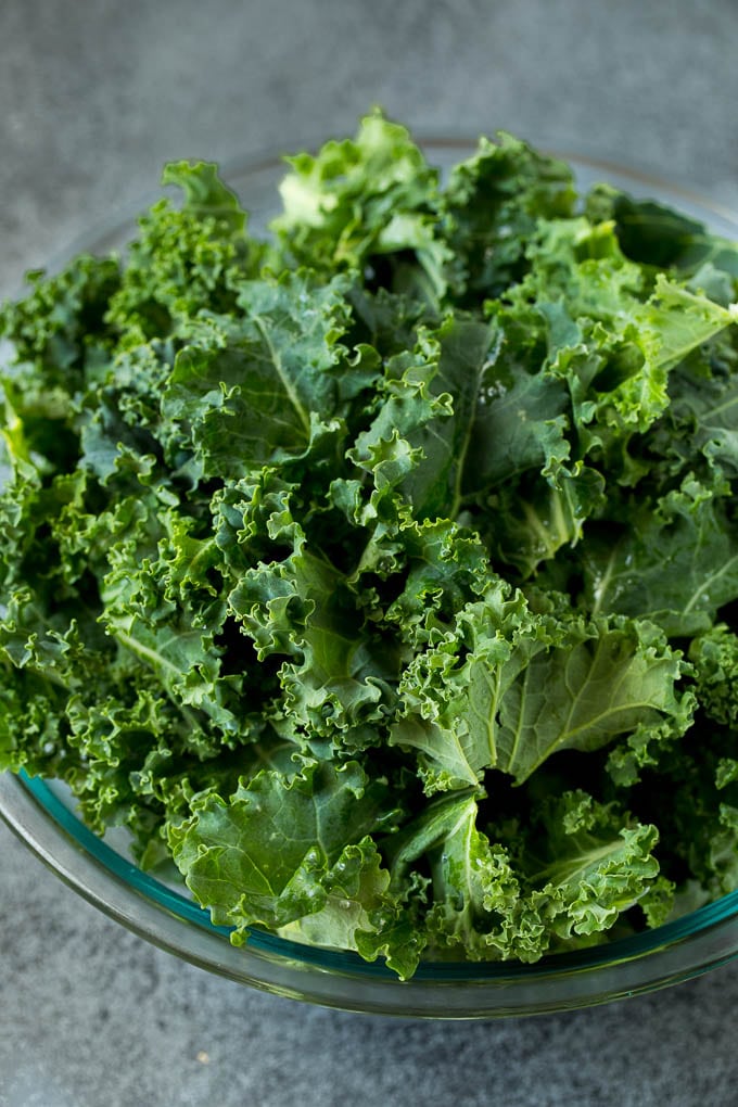 Sauteed kale flavored with olive oil and garlic, a quick and easy side dish! #kale #uzhal Chopped kale in a mixing bowl.