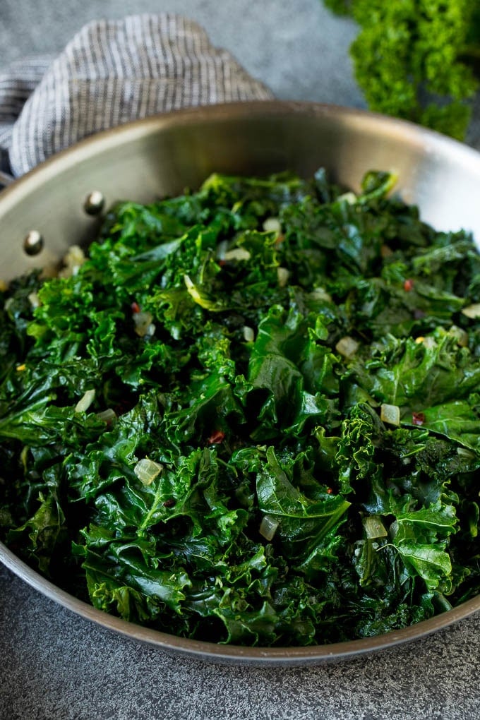 Sauteed kale flavored with olive oil and garlic, a quick and easy side dish! #kale #uzhal Cooked kale with olive oil, onions and garlic.