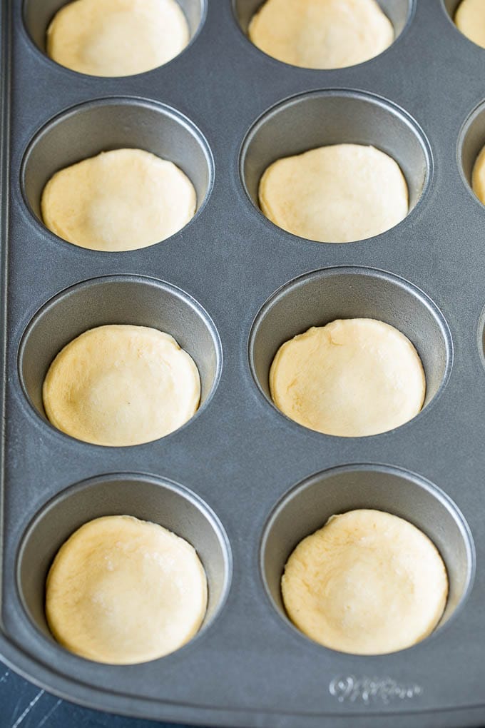 Mini pizzas topped with pepperoni are a fun and easy appetizer option. #pizza #uzhal #appetizer Dough circles pressed into muffin cups.