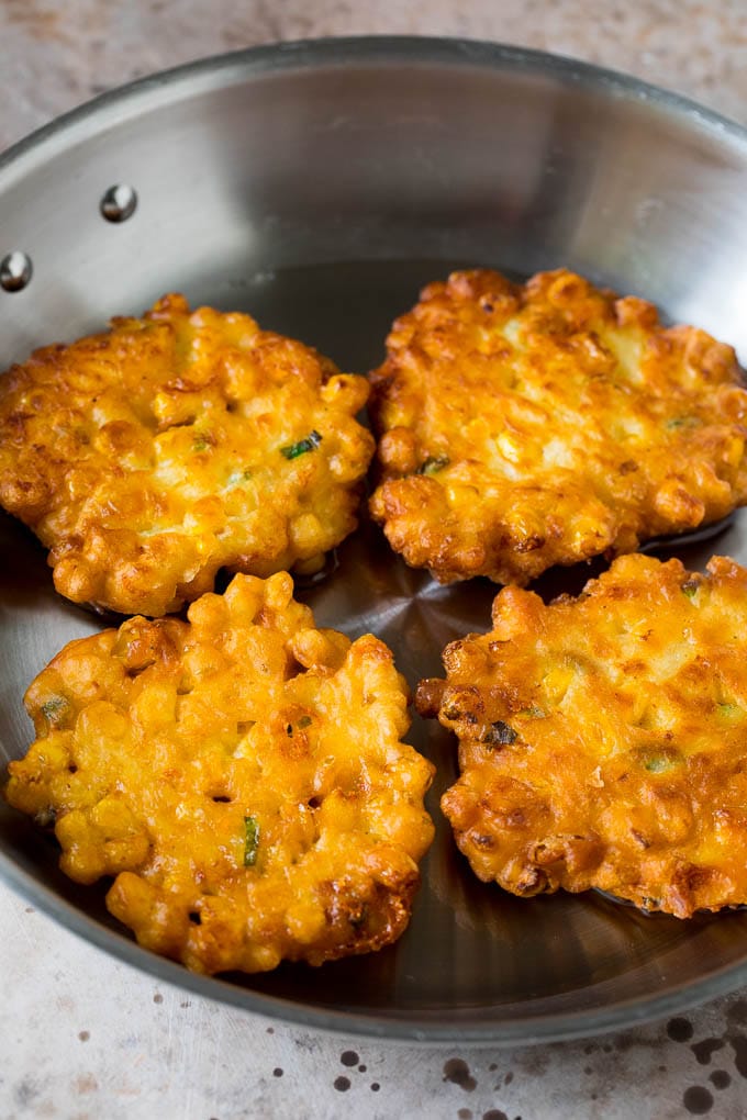 These crispy corn fritters are easy to make and are the perfect appetizer or lighter main course. #corn #uzhal Corn cakes in a pan of oil.