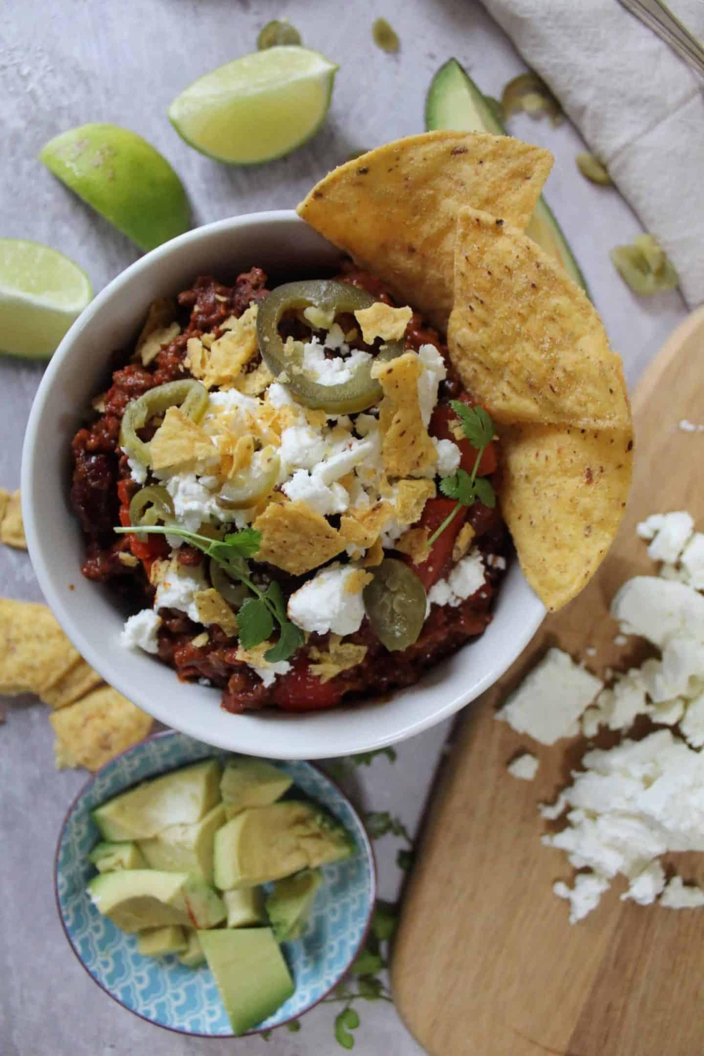 Chilli Con Carne Senza Glutine 2 Una ciotola di chilli con carne guarnita con nachos, feta e jalapeños.