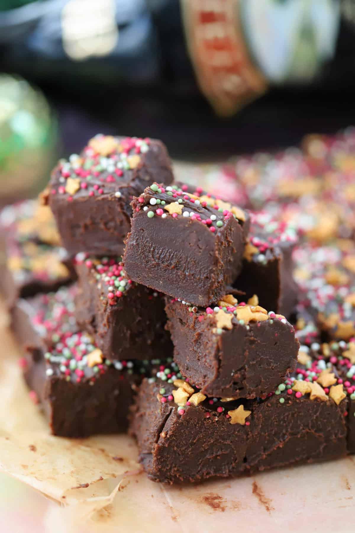 Fudge al Baileys 2 Un mucchio di pezzi di fudge al Baileys con una bottiglia di Baileys dietro.