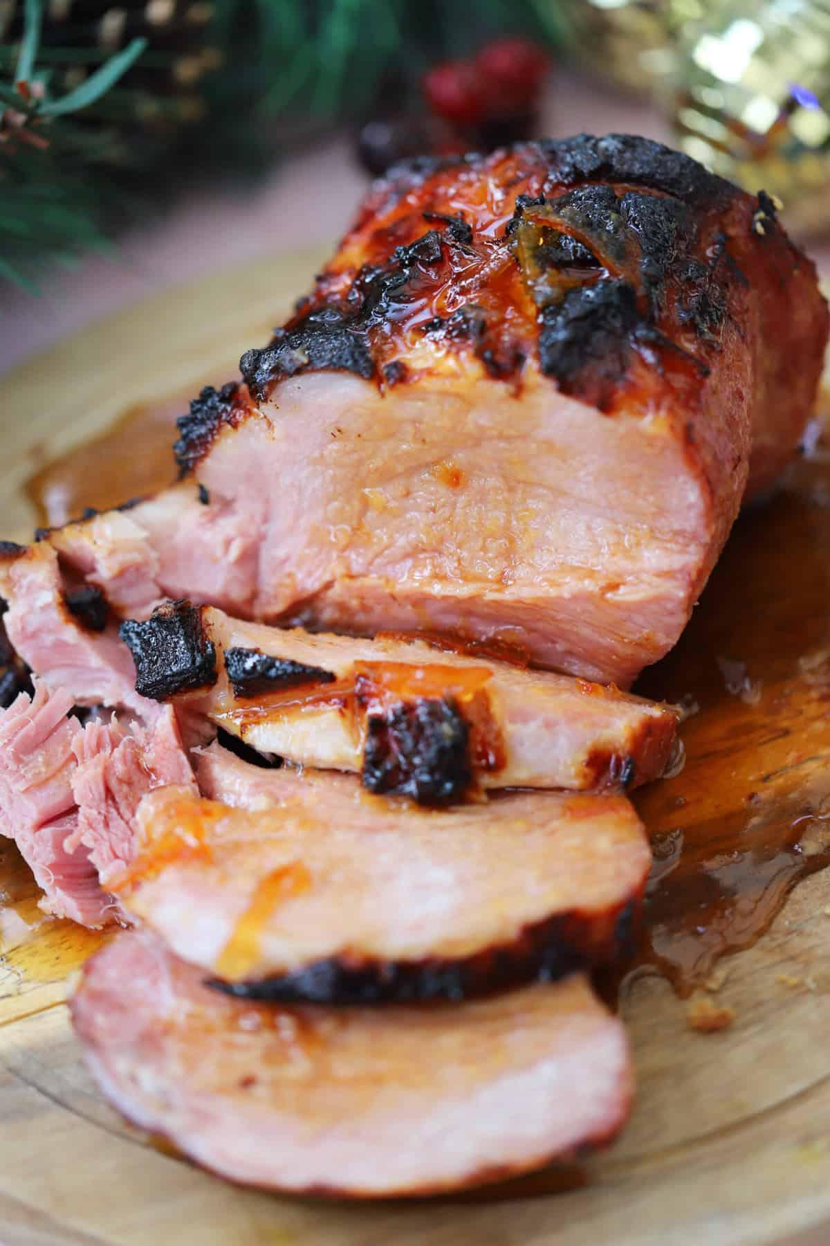 Un prosciutto cotto in slow cooker su un tagliere con glassa di marmellata.