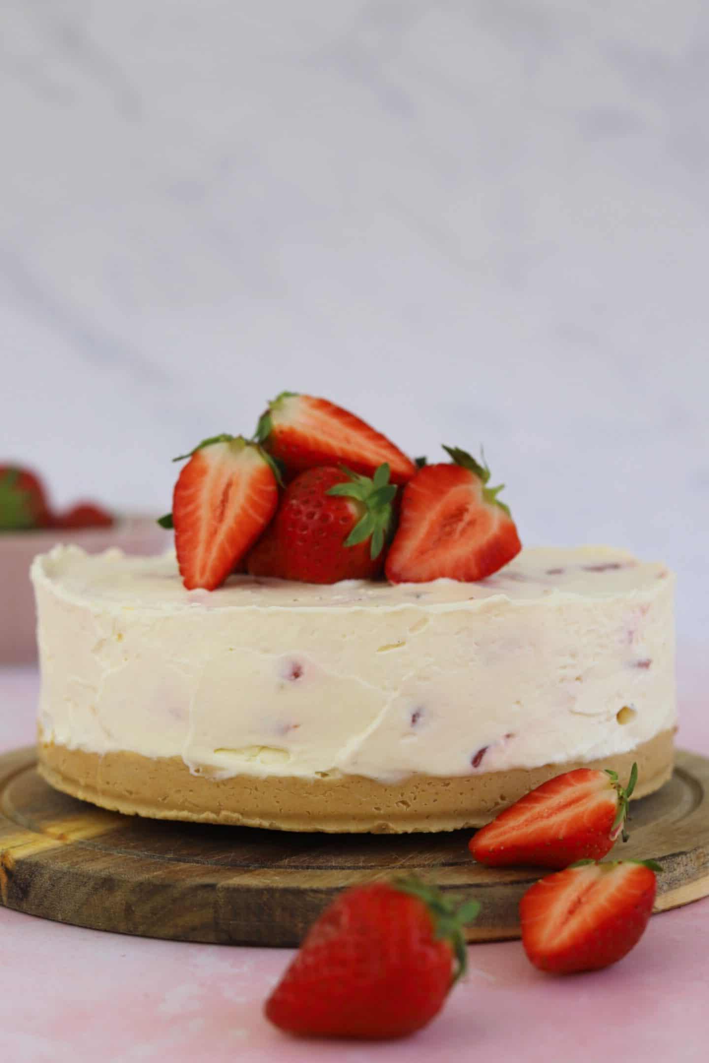 Cheesecake alla fragoga senza glutine 3 Una cheesecake alle fragole guarnita con fragole su un tagliere.