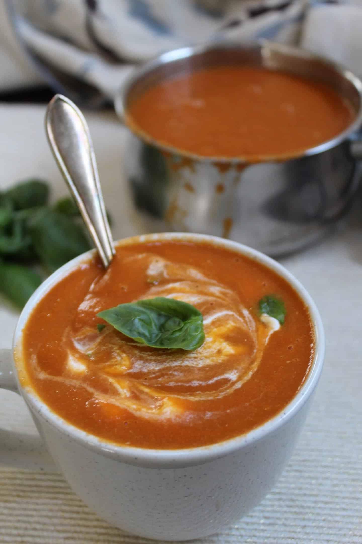 Zuppa di pomodoro senza glutine 3 Una tazza di zuppa di pomodoro senza glutine guarnita con una foglia di basilico fresco.